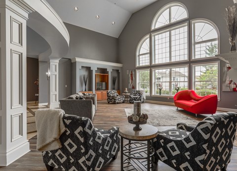 A living room with a red chair and a black and white patterned couch.