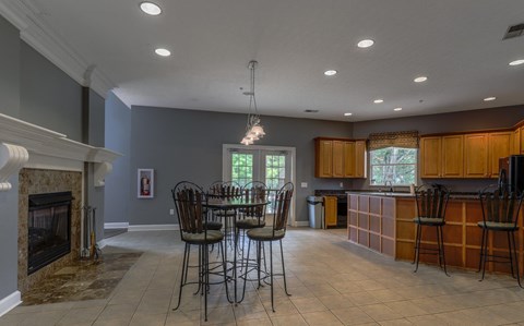 A kitchen with a table and chairs in front of a fireplace.