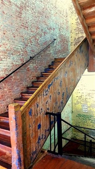the stairs are made of wood and are next to a brick wall