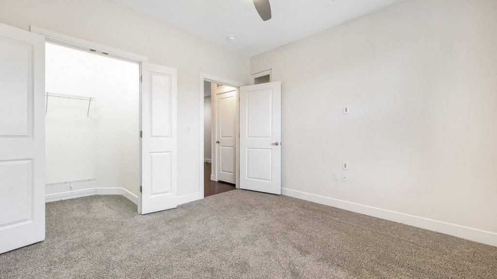 a bedroom with white walls and carpet and white doors at Vanguard Crossing, St. Louis