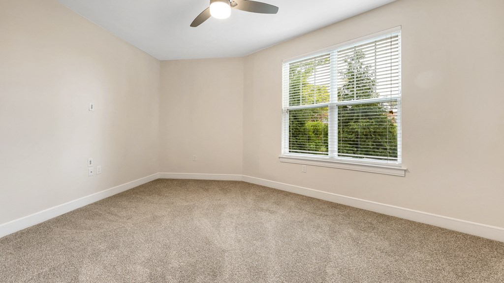 an empty bedroom with a large window and carpeting at Vanguard Crossing, Missouri 63124