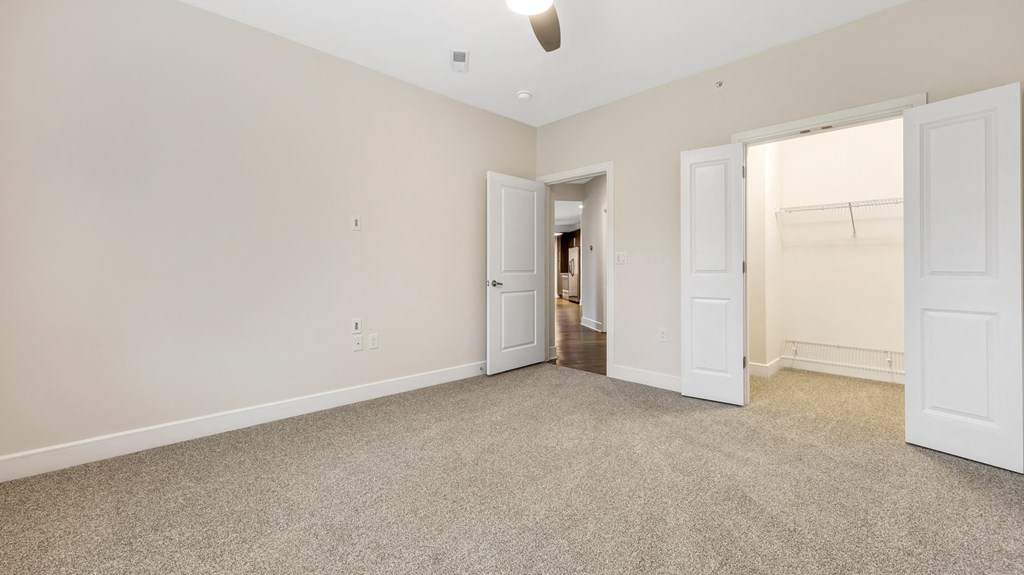 an empty living room with white doors and carpet at Vanguard Crossing, St. Louis, Missouri