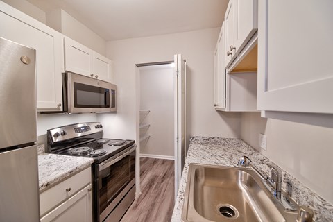 a kitchen with white cabinets and stainless steel appliances and granite counter tops