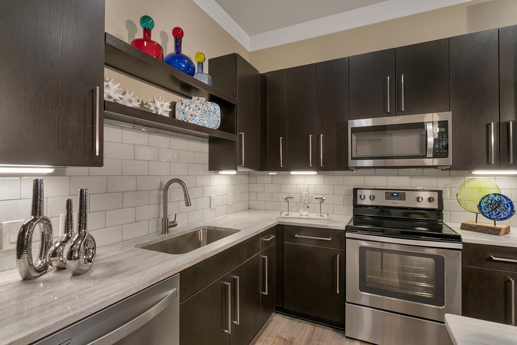 a kitchen with stainless steel appliances and black cabinets at Aster Apartments, Beachwood