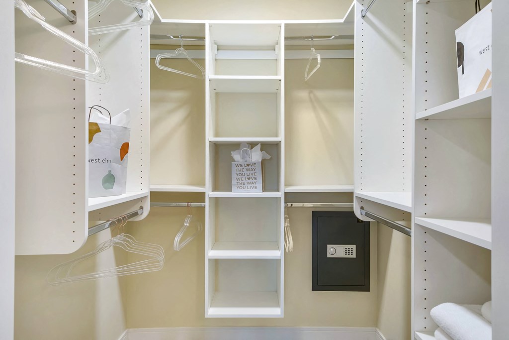 a walk in closet with white shelving and shelves and a door at Aster Apartments, Beachwood, 44122