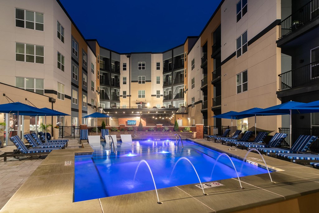 a large swimming pool in front of an apartment building at night at Aster Apartments, Beachwood, OH 44122