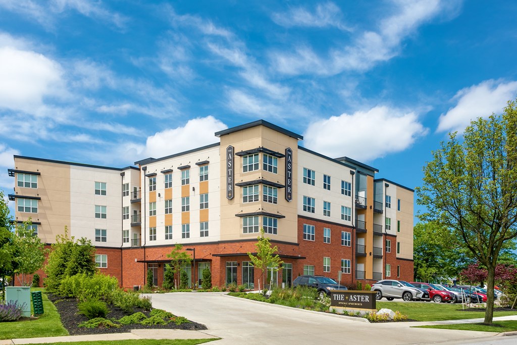 a large apartment building with cars parked in front of it at Aster Apartments, Beachwood