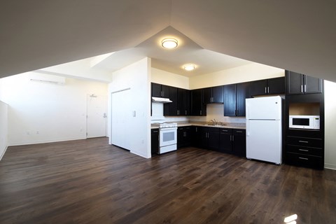 an empty kitchen with black cabinets and white appliances