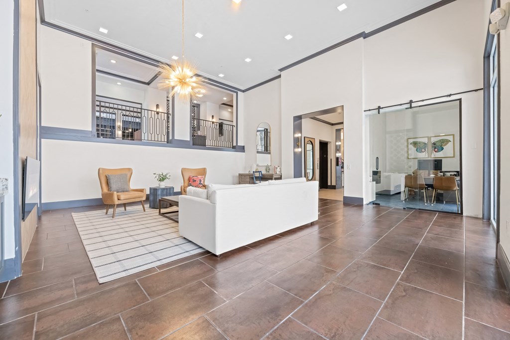 A spacious living room with a white sofa and wooden chairs at Aster Apartments, Beachwood