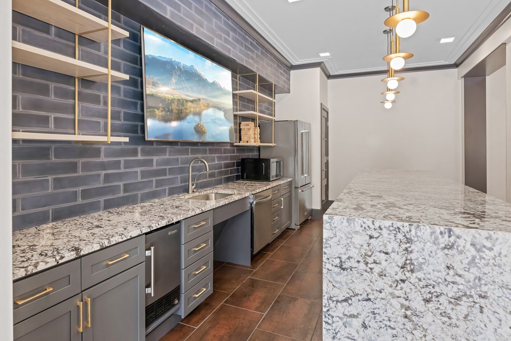 A kitchen with a marble countertop and a painting of a lake on the wall at Aster Apartments, Beachwood Ohio