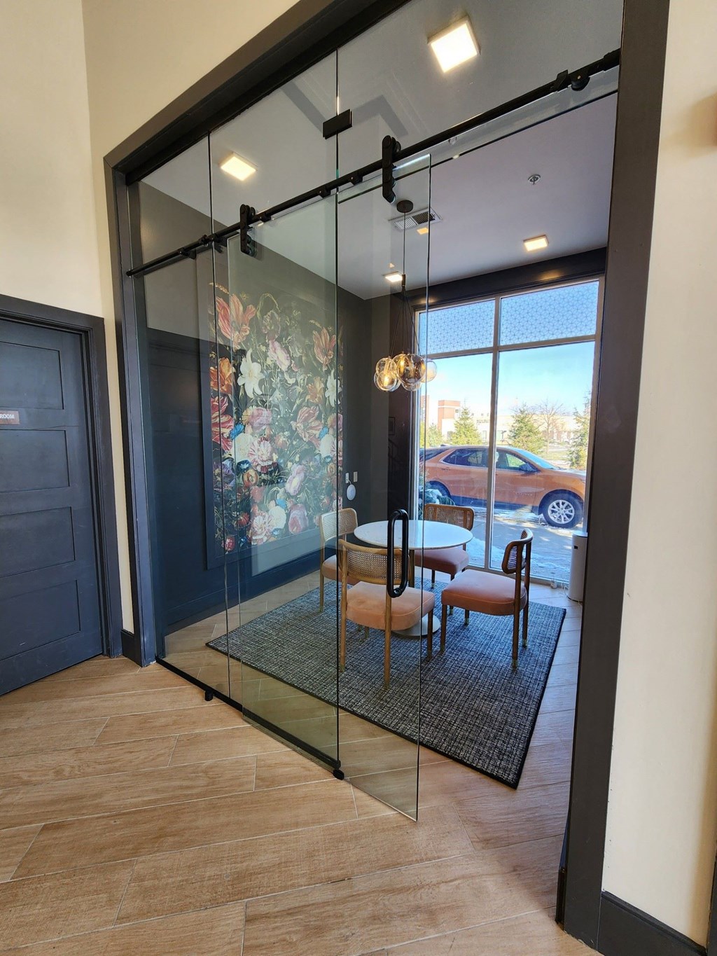 A glass door with a black frame leads to a balcony with a table and chairs at Aster Apartments, Ohio