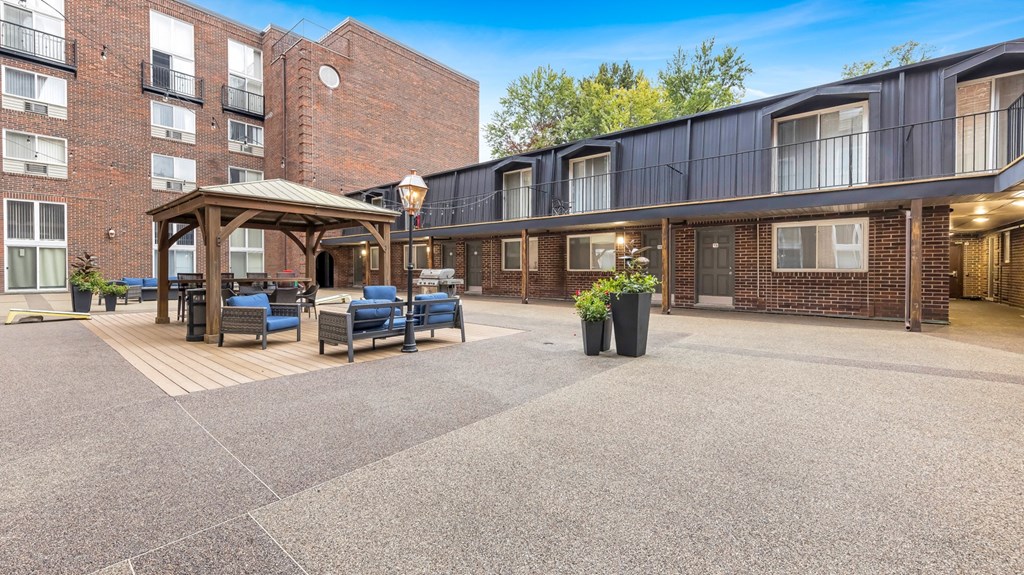 a courtyard with furniture and a gazebo in front of a brick building
