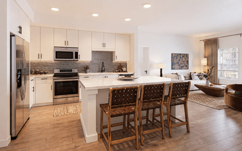 A modern kitchen with a large island and wooden chairs.