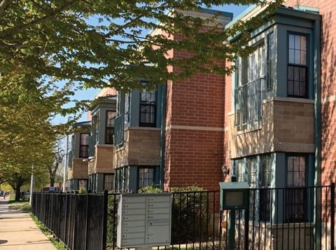 A row of houses with green shutters and a black fence.