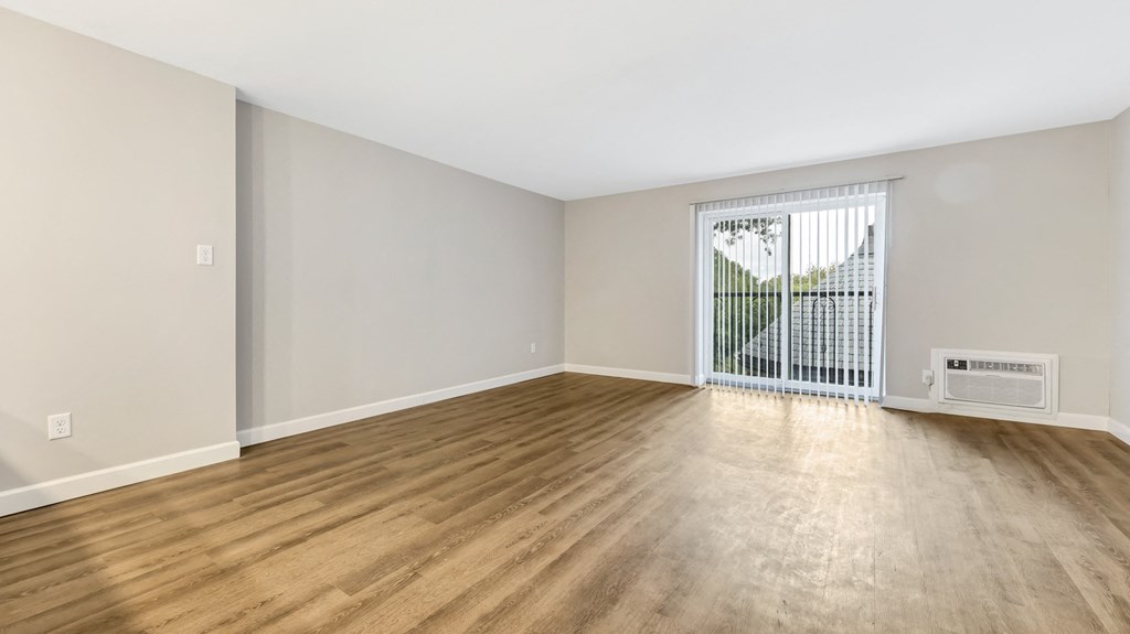 an empty living room with wood flooring and a window