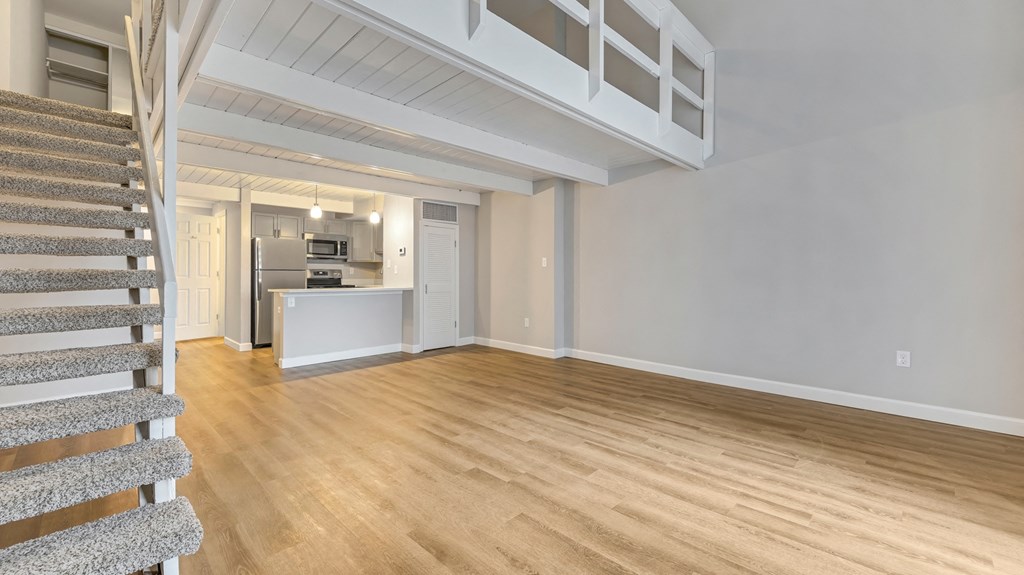 the living room and kitchen of a house with wood floors and a staircase