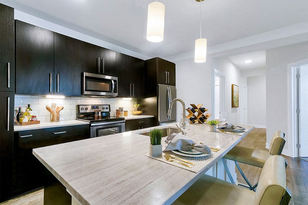 a kitchen with black cabinets and a wooden table at Aster Apartments, Beachwood