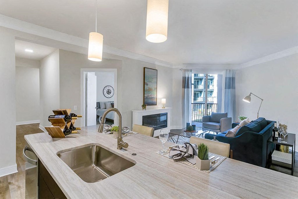 a kitchen with a sink and a counter in front of a living room at Aster Apartments, Ohio, 44122