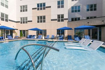 a pool with blue and white chairs and a building in the background at Aster Apartments, Ohio