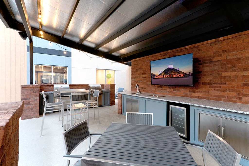 a patio with a table and chairs and a tv at Aster Apartments, Beachwood, OH