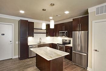 a kitchen with stainless steel appliances and wooden cabinets at Aster Apartments, Beachwood