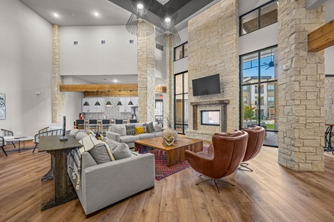 A living room with a grey couch, a brown chair and a stone fireplace.