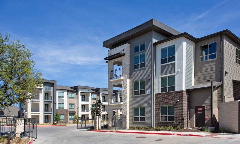 a row of apartment buildings on the side of a street at Hunters Creek Apartments, Denton, TX 76210