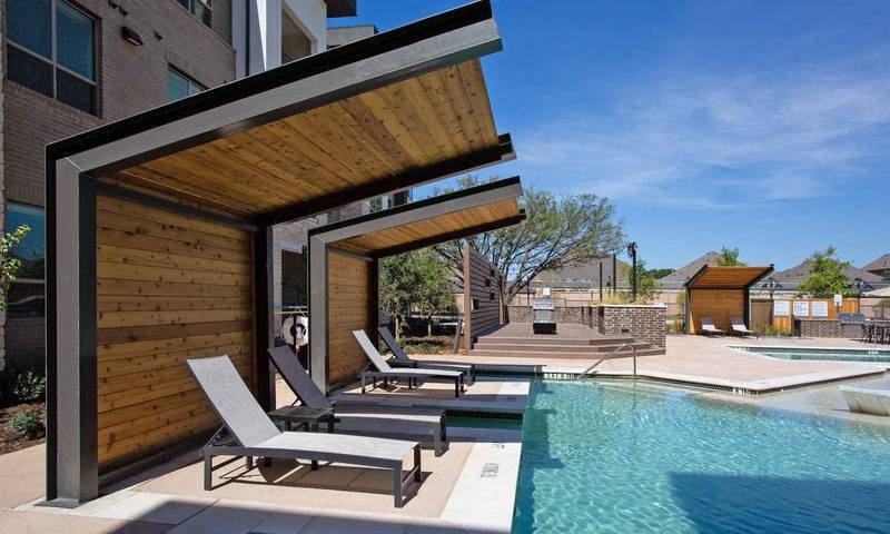 a pool with two lounge chairs next to a building at Hunters Creek Apartments, Texas, 76210