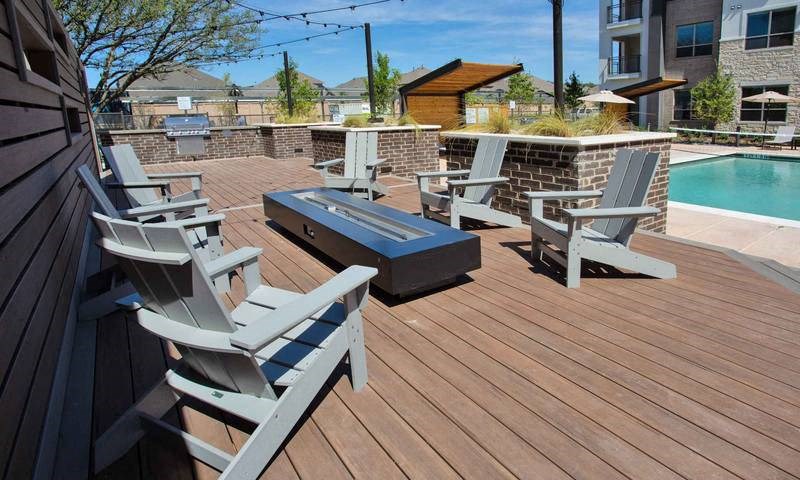 a group of chairs on a deck next to a pool at Hunters Creek Apartments, Denton