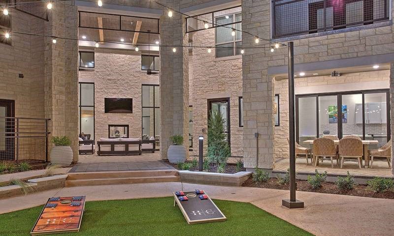 a view of a building with a courtyard with grass and a fountain at Hunters Creek Apartments, Denton, TX