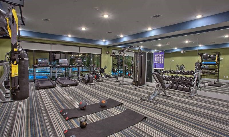 a gym with a lot of machines in it at Hunters Creek Apartments, Texas