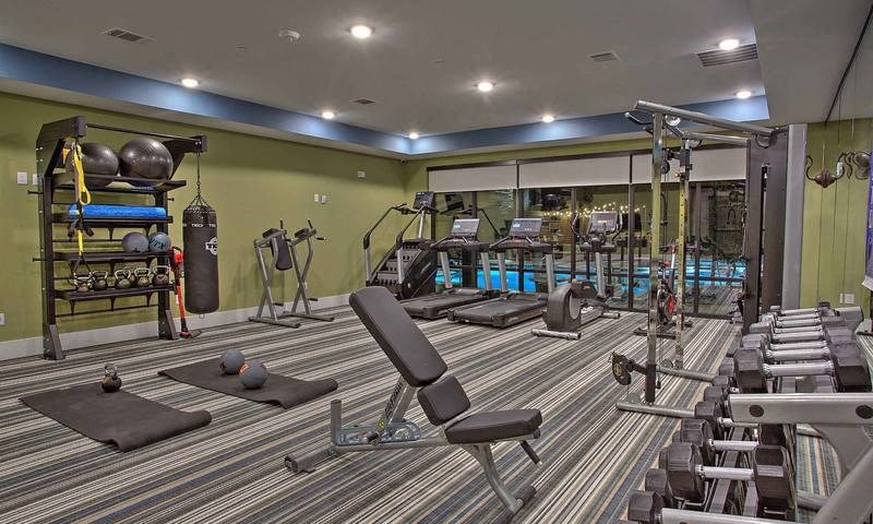 a gym with a lot of chairs and weights at Hunters Creek Apartments, Denton