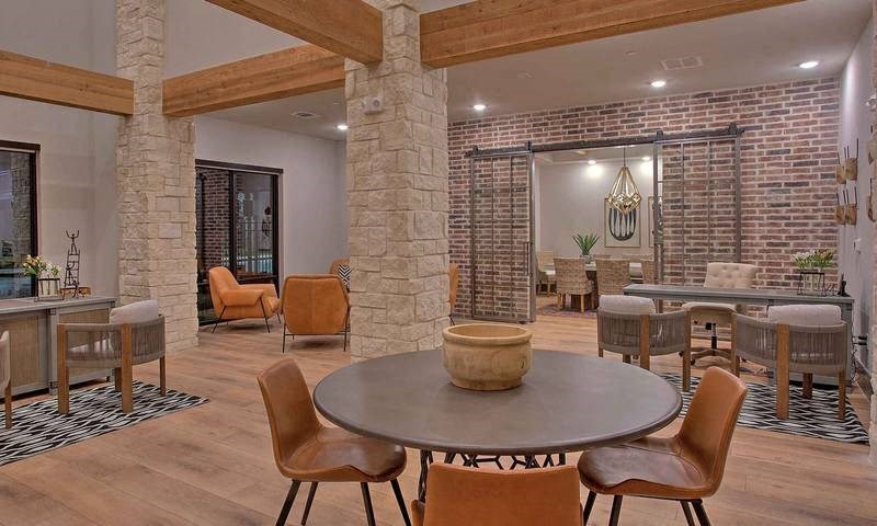 a living room with a table and chairs and a brick wall at Hunters Creek Apartments, Texas