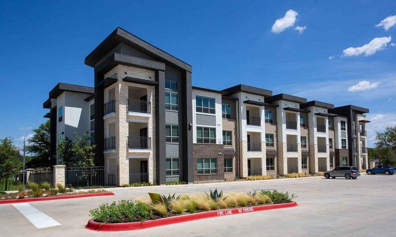 a row of apartment buildings with a parking lot at Hunters Creek Apartments, Denton, TX 76210