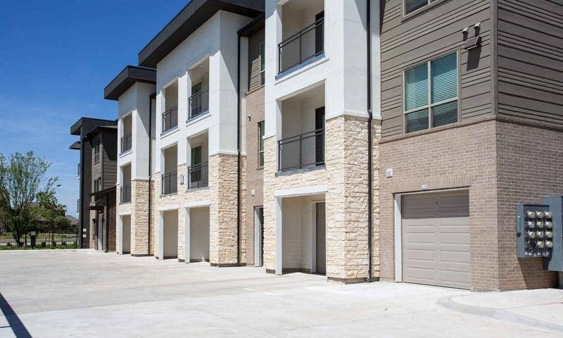 a row of brick apartment buildings with garage doors at Hunters Creek Apartments, Denton, TX