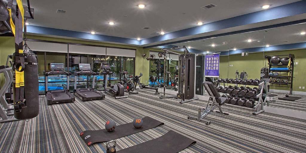 a gym with a lot of machines and weights at Hunters Creek Apartments, Denton Texas