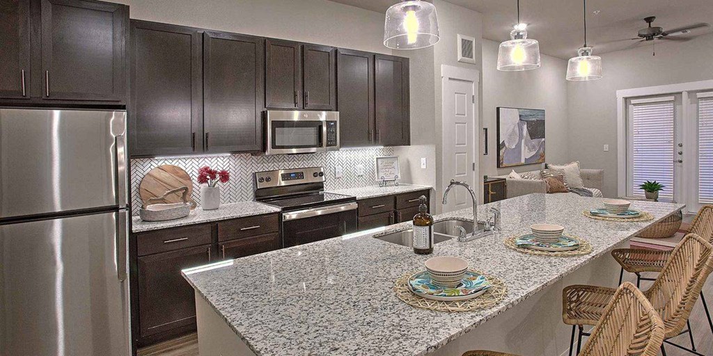 a kitchen with stainless steel appliances and a granite counter top at Hunters Creek Apartments, Texas, 76210