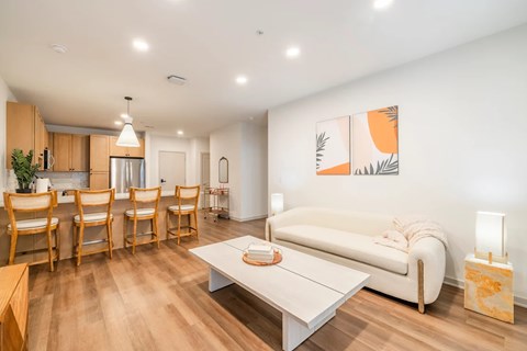 A living room with a white couch, wooden chairs, and a painting on the wall.