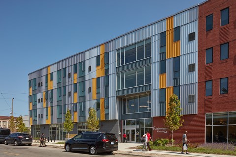 A modern building with a glass facade and a red brick building next to it.