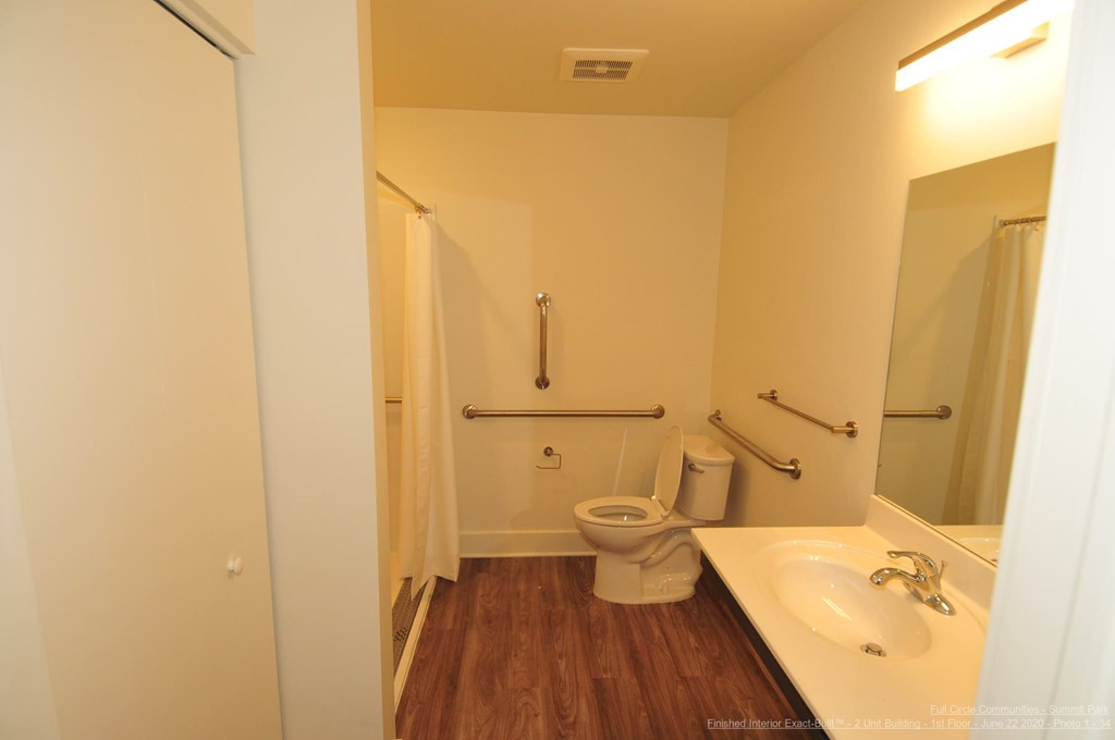 A bathroom with a toilet, sink, and mirror.