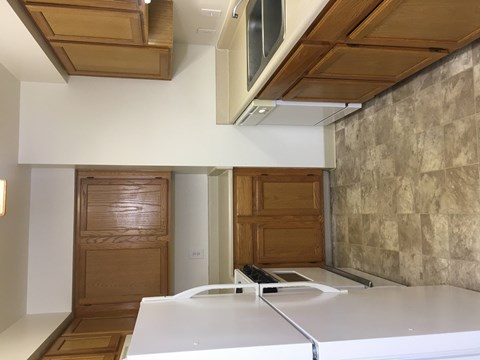 A kitchen with a white counter top and wooden cabinets.