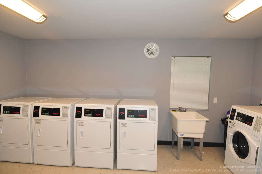 A row of white front load washing machines in a laundry room.
