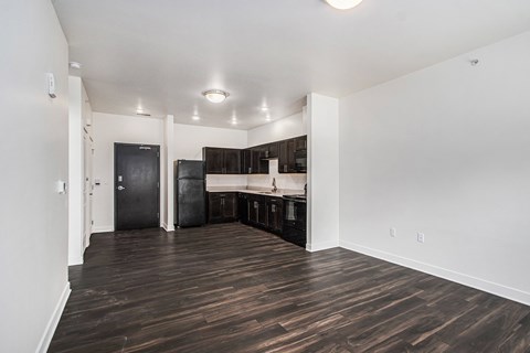 A kitchen area with dark wood floors and white walls.