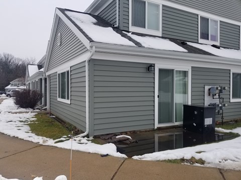 A house with a grey siding and a black mailbox.