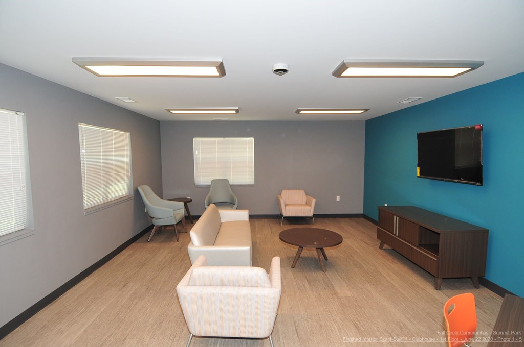 A living room with a white couch, a brown coffee table, and a flat screen TV mounted on the wall.