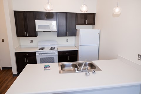 A kitchen with a white counter top and a white sink.