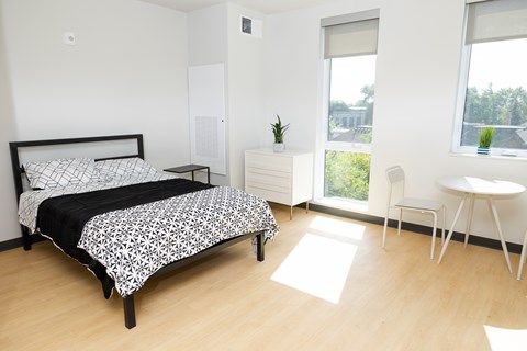 A bedroom with a bed, a nightstand, a chair, and a window.