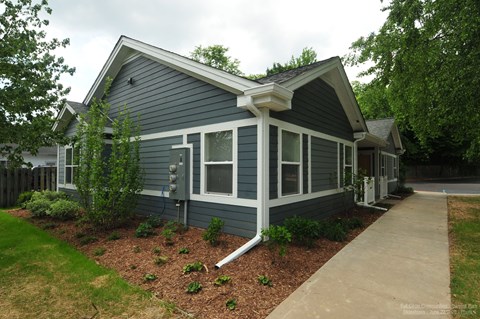 A small house with a grey siding and white trim.