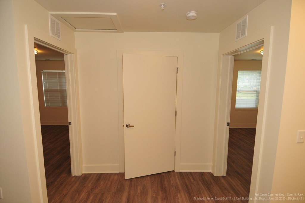 A white door is in the middle of a room with wood floors.