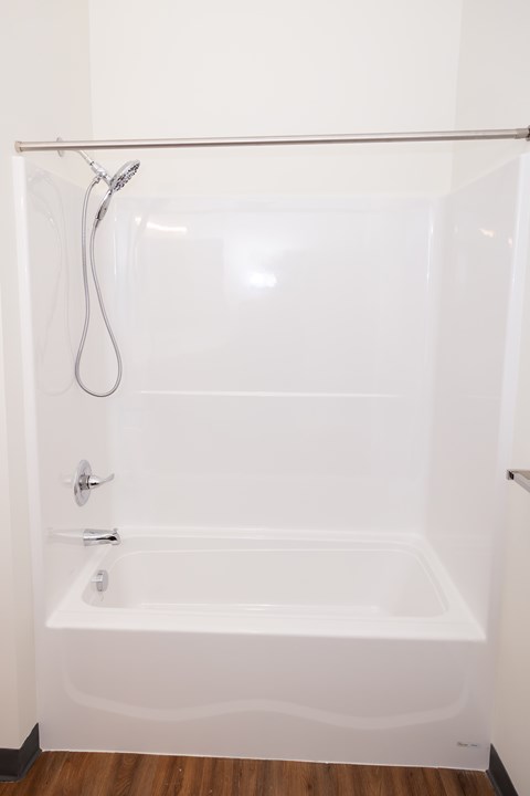 A white bathtub with a shower head and faucet.